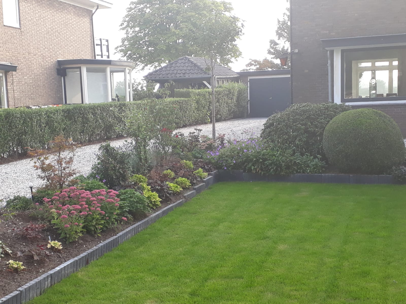 Aangelegde voortuin met borders, hagen en gazon