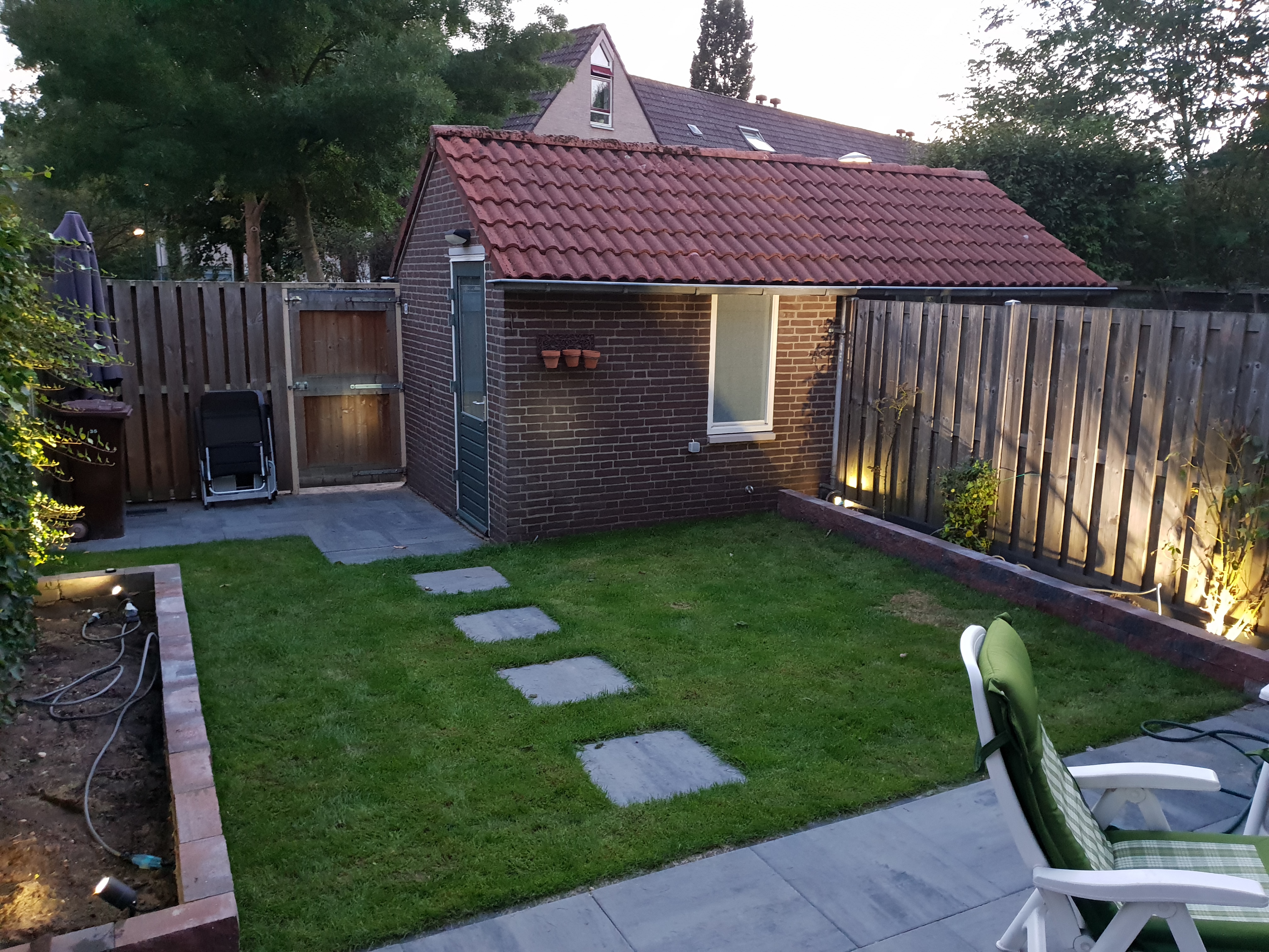 Door Westeneng aangelegde achtertuin met tuinverlichting in de avond